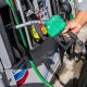 A man wearing a checked shirt and jeans returns a fuel nozzle after refueling a vehicle with diesel at a Chevron petrol station.