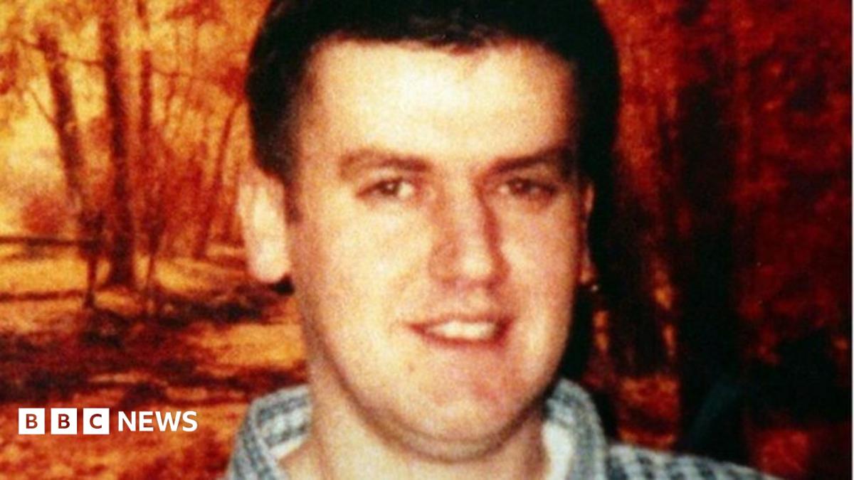 Robert Hamill with brown hair and a checked shirt smiling at the camera.