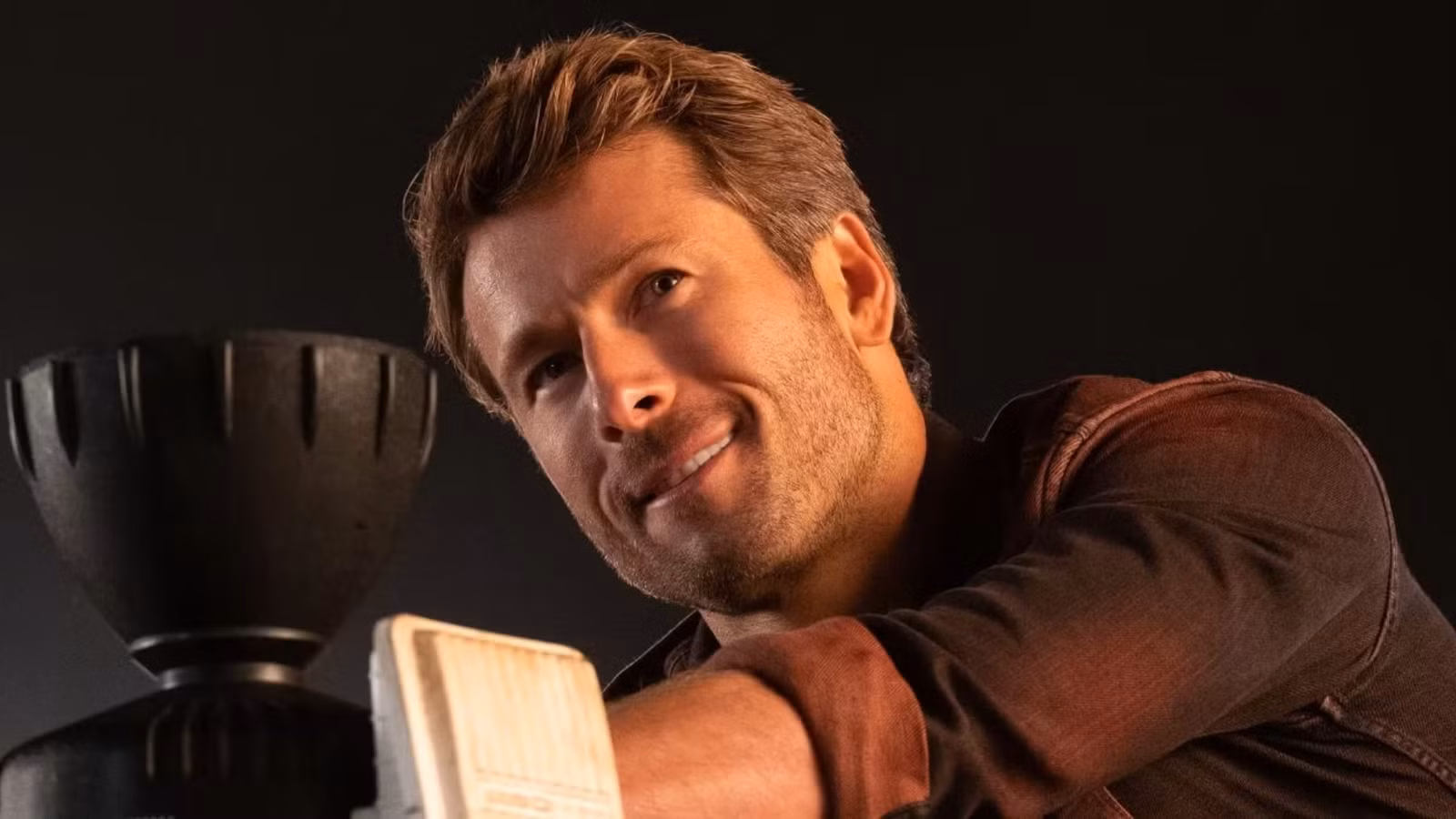 Glen Powell as Tyler Owens, smiling, in Twisters.