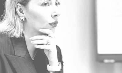 pinterest graphic reads THE ULTIMATE GUIDE TO BLAZERS FOR WOMEN; in the background a professional young woman in blazer has contemplative expression on her face; she is holding a piece of paper