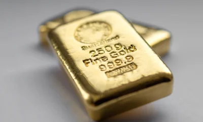 Two gold bullions weighing 250 grams each on a grey background.