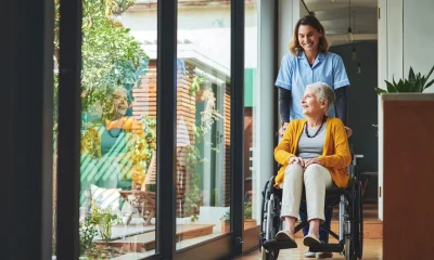 Shot of a young nurse pushing a senior woman in a wheelchair in a retirement home