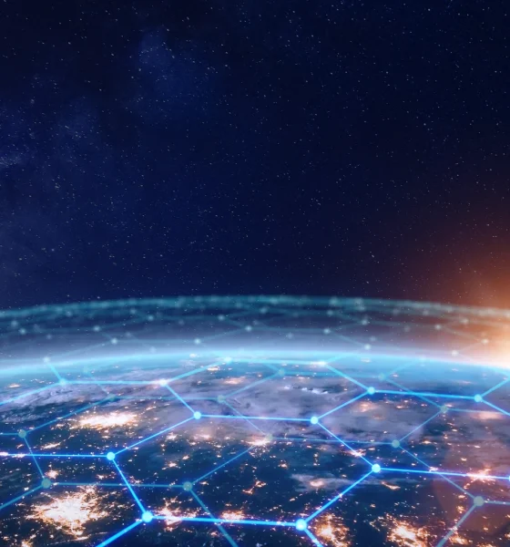 Communication network above Earth for global business and finance digital exchange. Internet of things (IoT), blockchain, smart connected cities, futuristic technology concept. Satellite view.