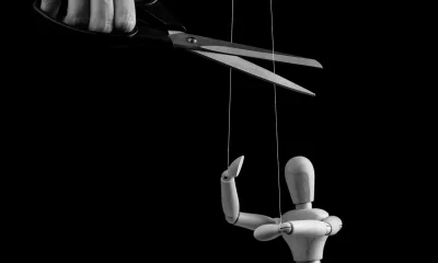 Hand cutting strings over puppet with scissors. Manipulation, negative influence, control stop concept. Overcoming addiction. Black and white