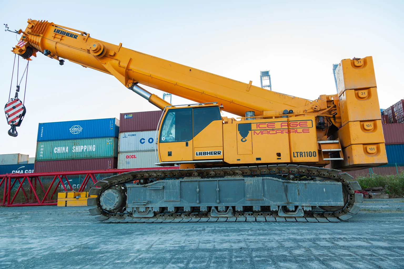 A heavy crawler crane stands on the territory of a container terminal.