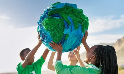 Group of young climate activists holding up a globe together by the sea