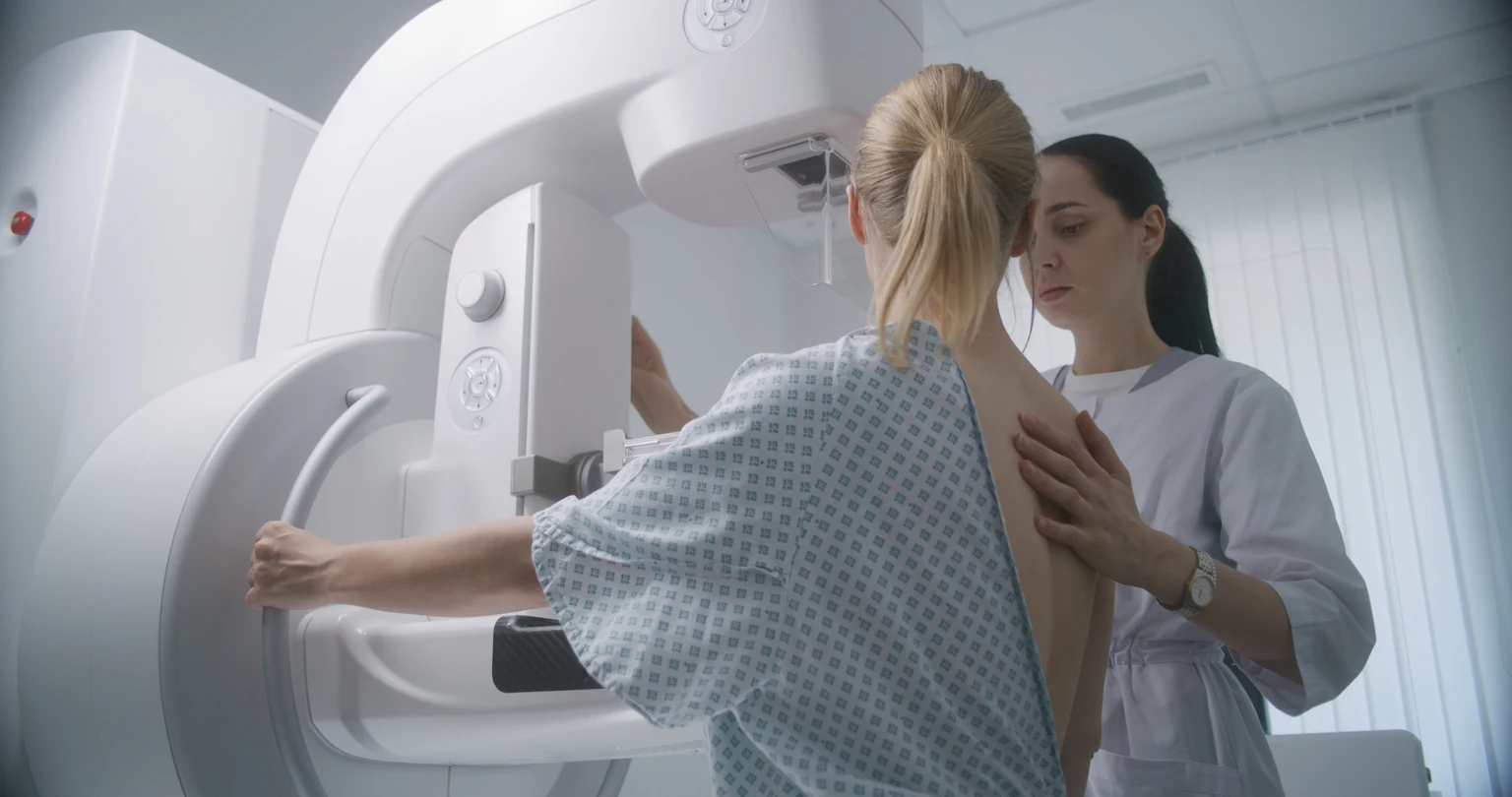 Una doctora ajusta la moderna máquina de mamografía para el paciente