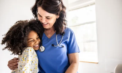 Young girl embracing nurse in doctors office