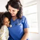Young girl embracing nurse in doctors office