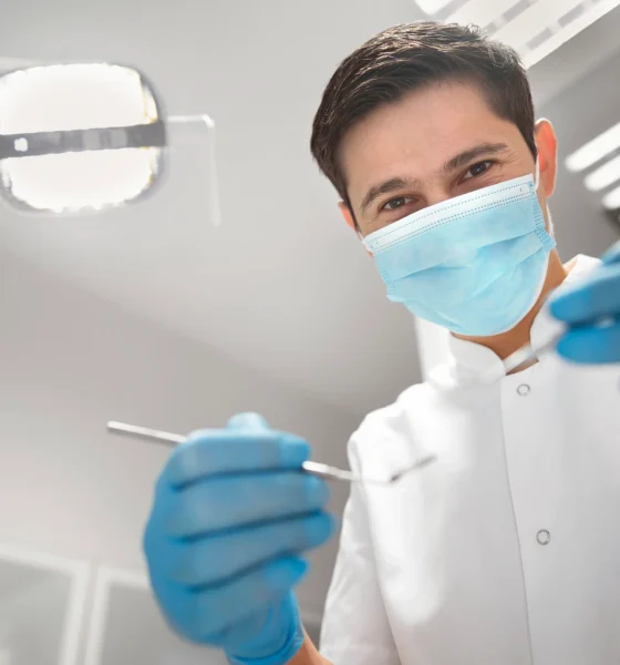 Dentist holding dental equipment in clinic