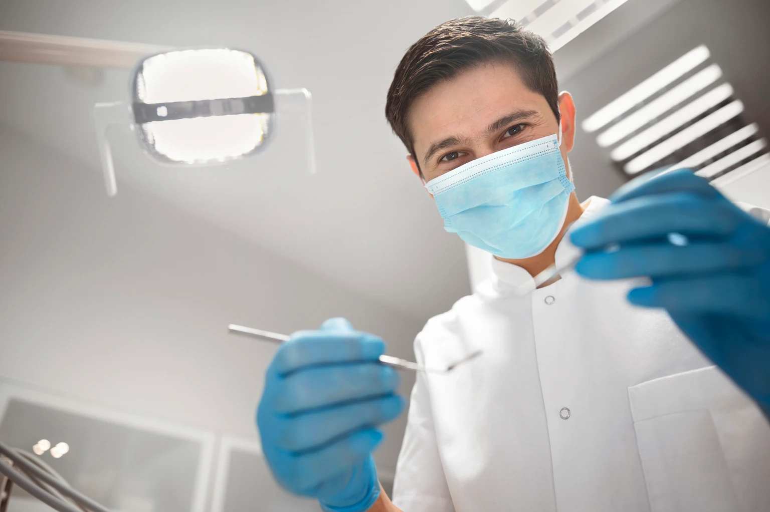Dentist holding dental equipment in clinic