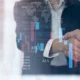 Business finance and investment background, global business and data analysis concept. Businessmen making a handshake with economic graph growth chart, business development, joint venture