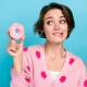 Close up photo of young lady wear pink trendy jumper strawberry print bite lips wish try eat hungry donut isolated on blue color background