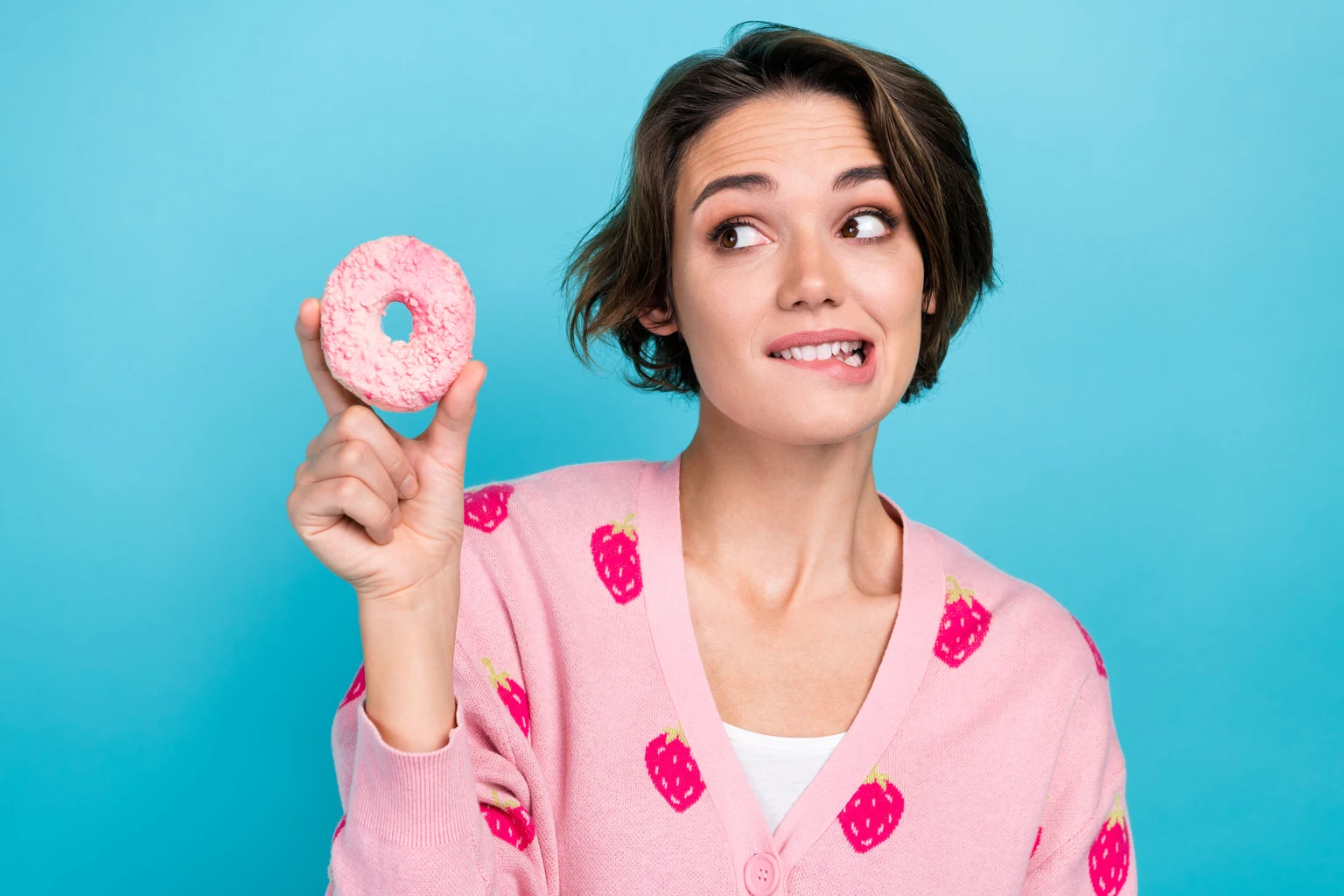 Close up photo of young lady wear pink trendy jumper strawberry print bite lips wish try eat hungry donut isolated on blue color background