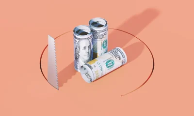 Rolled American One Hundred Dollars Bills And Handsaw On Orange Background