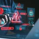 Cybersecurity threat warning concept with holographic red alert symbols over hands using laptop in dark environment, illustrating data protection risks.