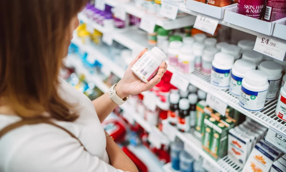Woman choosing vitamins in pharmacy aisle