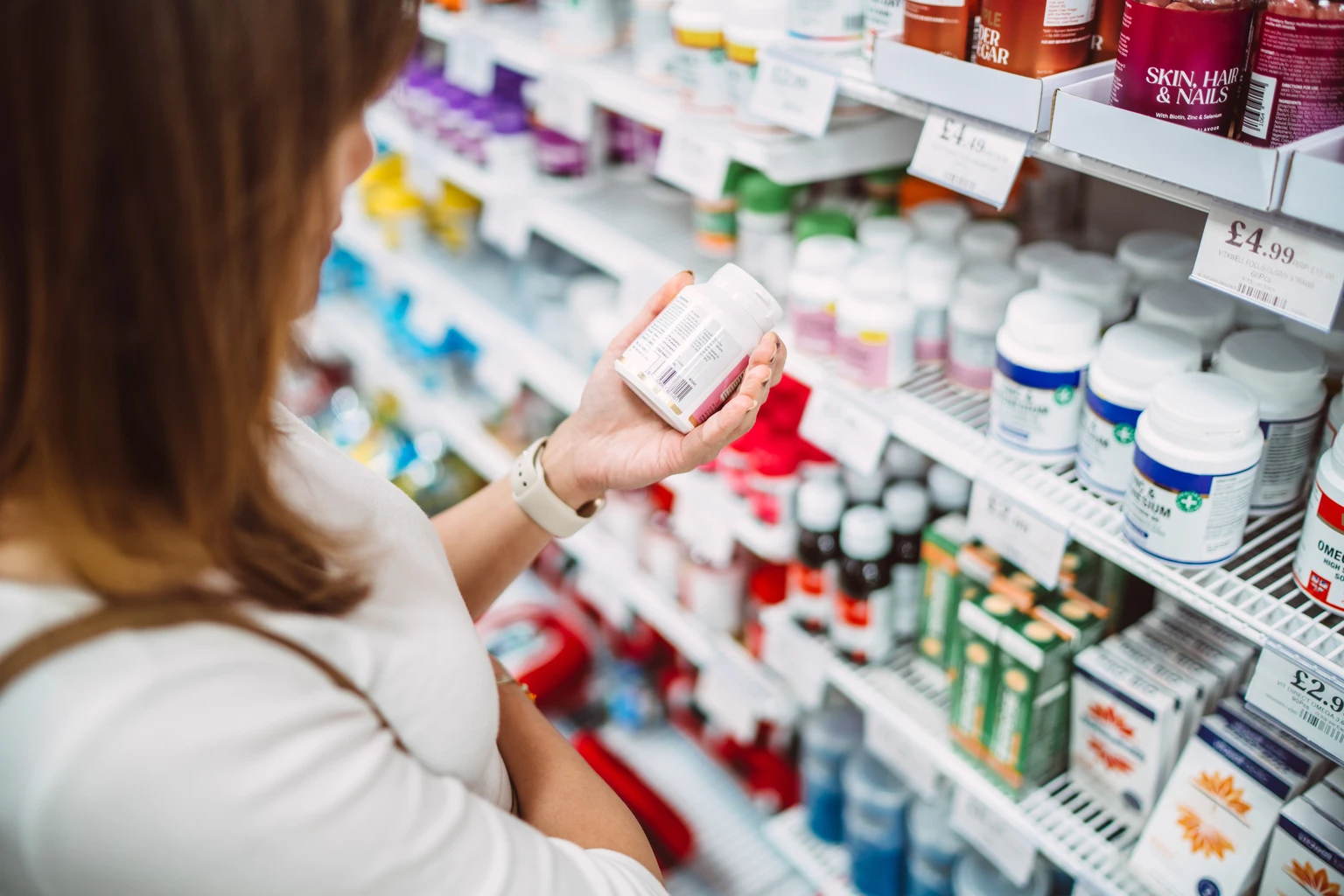 Woman choosing vitamins in pharmacy aisle