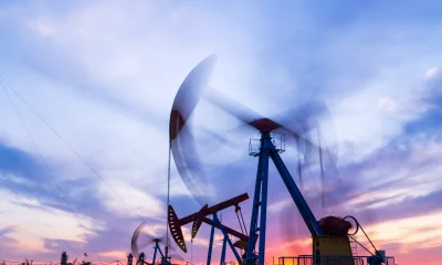 Oil field site, in the evening, oil pumps are running, The oil pump and the beautiful sunset reflected in the water