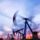 Oil field site, in the evening, oil pumps are running, The oil pump and the beautiful sunset reflected in the water
