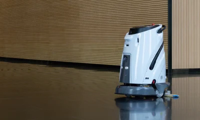 robotic cleaner or Modern floor cleaner glides across polished surface. Smooth motion reflects in glossy, dark floor. Warm wood paneling lines the background. Clean, quiet scene suggests efficiency and order.