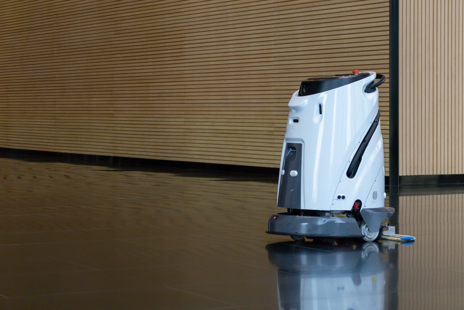 robotic cleaner or Modern floor cleaner glides across polished surface. Smooth motion reflects in glossy, dark floor. Warm wood paneling lines the background. Clean, quiet scene suggests efficiency and order.