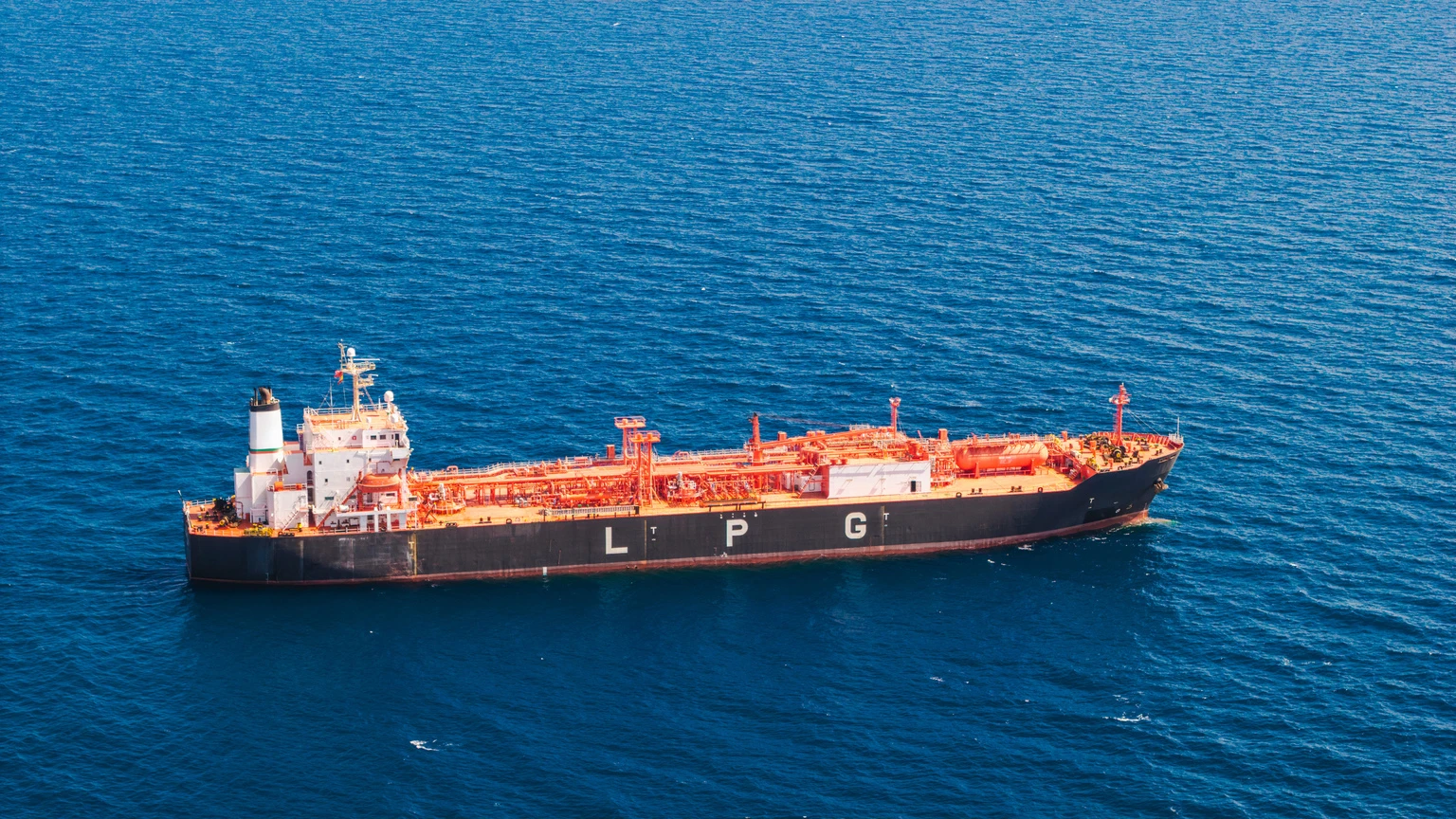 Vista aérea cercana de un buque petrolero de GLP transportando gas licuado de petróleo a través del profundo mar Mediterráneo, azul profundo.