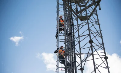Engineers climbing transmission tower, low angle view