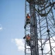 Engineers climbing transmission tower, low angle view