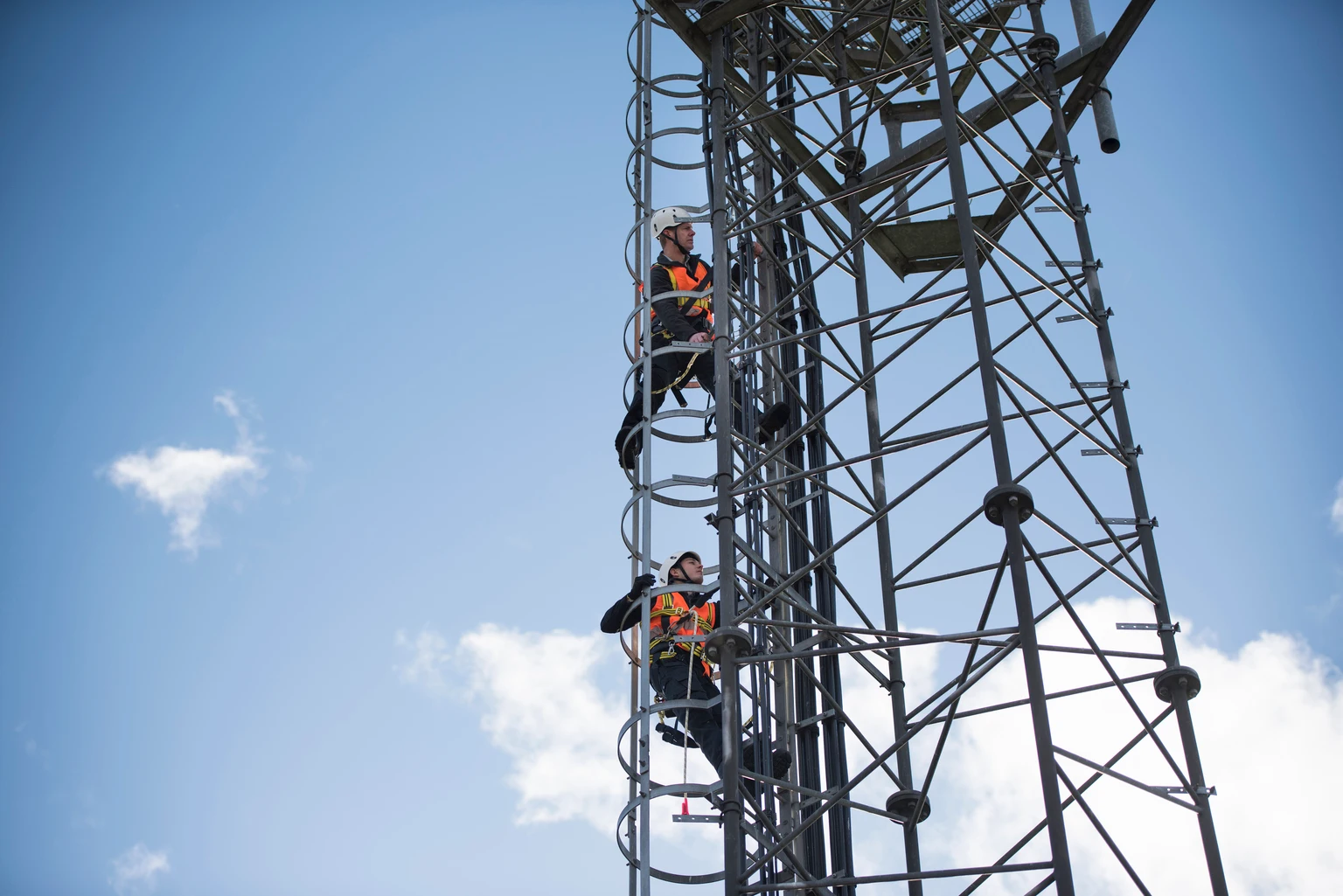 Engineers climbing transmission tower, low angle view
