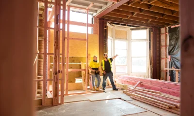 Two construction workers talk together inside large house under renovation