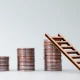 Three pile of coins and a small wooden ladder.