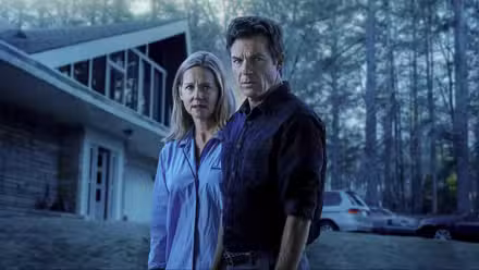 Jason Bateman as Marty Byrde and Laura Linney as Wendy Byrde standing in front of a house on the show Ozark