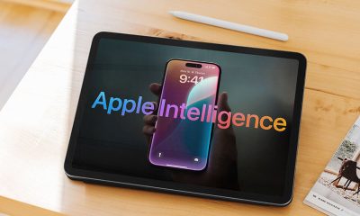 Hand holding smartphone reflecting on tablet screen displaying apple intelligence