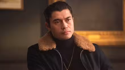 Henry Golding sits listening in The Gentlemen