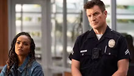 Mekia Cox and Nathan Fillion listening to someone in a police office.