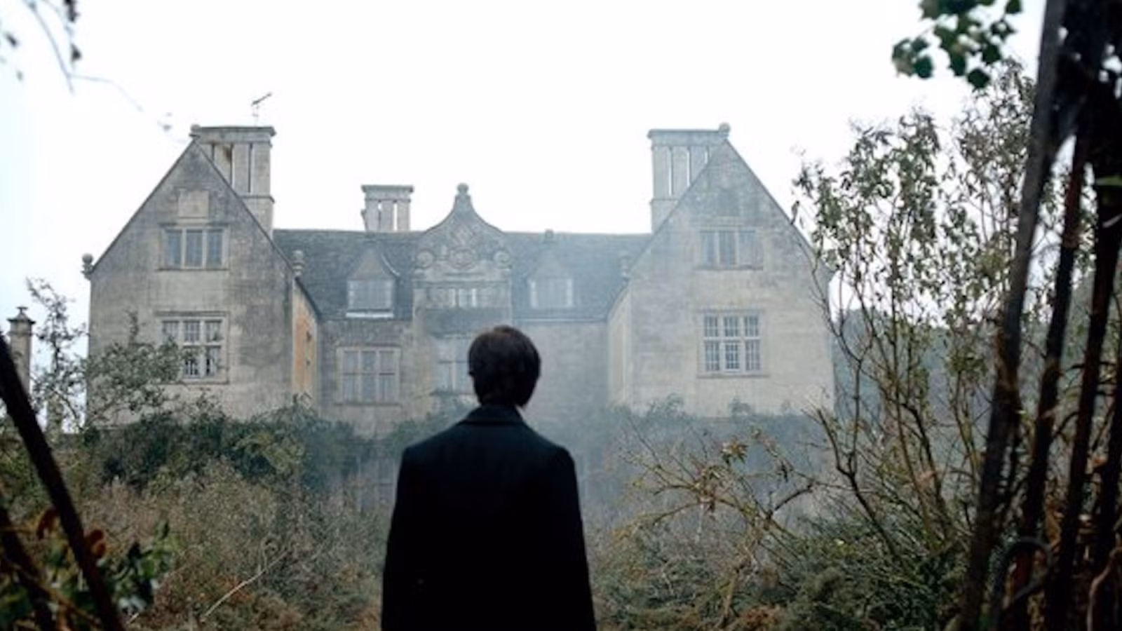 Arthur Kipps standing in front of Eel Marsh House in The Woman in Black.