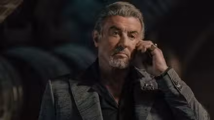 Sylvester Stallone holding a mobile phone up to his ear in Tulsa King Season 3, Episode 3.