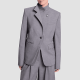 woman wears unusual blazer with two lapels, one buttons high on your neck and the other is a regular blazer lapel