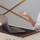 Woman sighs in exasperation at something on her laptop; she has taken off her eyeglasses and holds one hand out in a WTF gesture