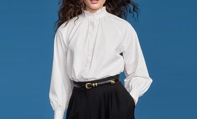 A woman wearing a long-sleeved white blouse, black pants, and black belt
