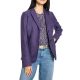 A woman wearing blue jeans, a purple print top, purple blazer, and gold belt