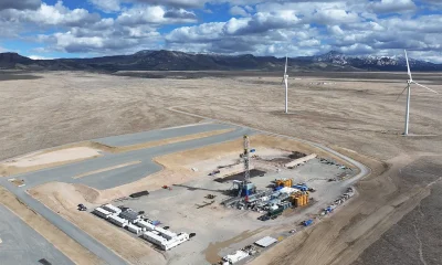 a tall thin scaffold surrounded by tanks protrudes from the desert