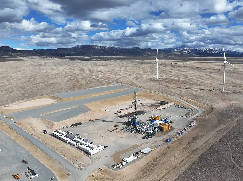 a tall thin scaffold surrounded by tanks protrudes from the desert