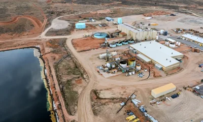 an aerial view of a complex of industrial buildings and large aboveground tanks near a large artific