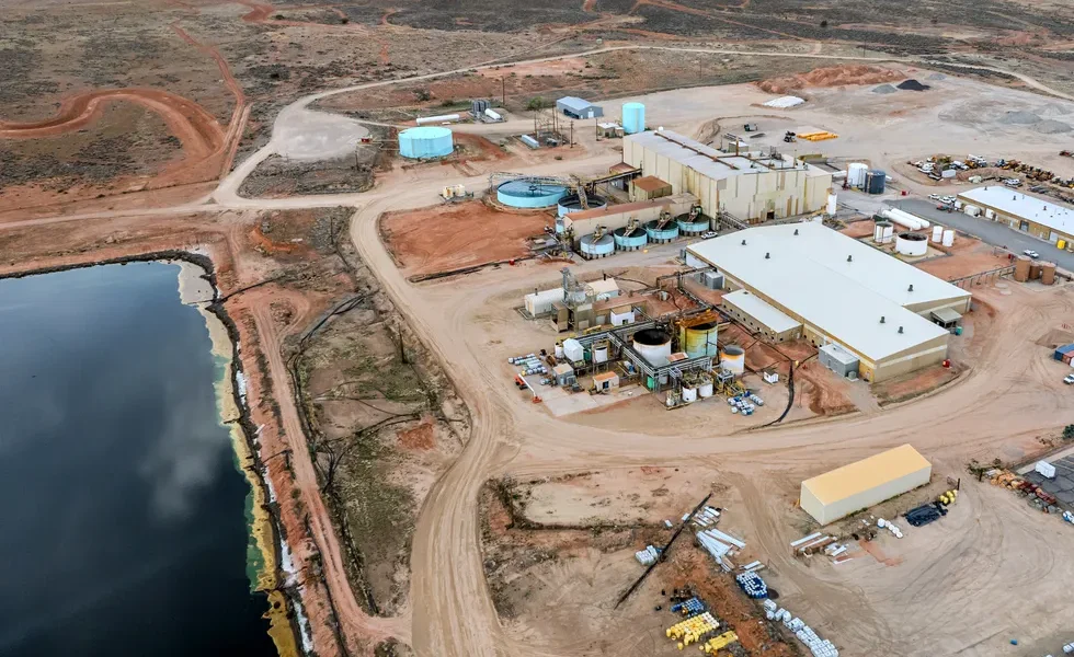 an aerial view of a complex of industrial buildings and large aboveground tanks near a large artific