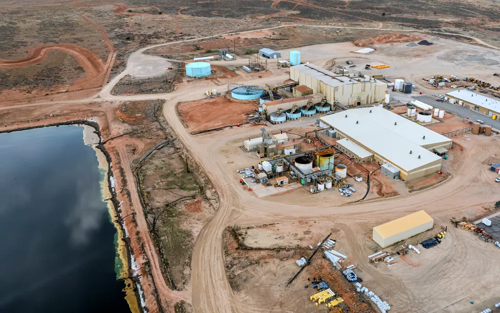 an aerial view of a complex of industrial buildings and large aboveground tanks near a large artific