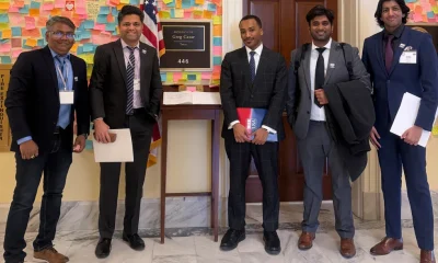 group of five men standing outside an office with a placard that reads representative greg casar tex
