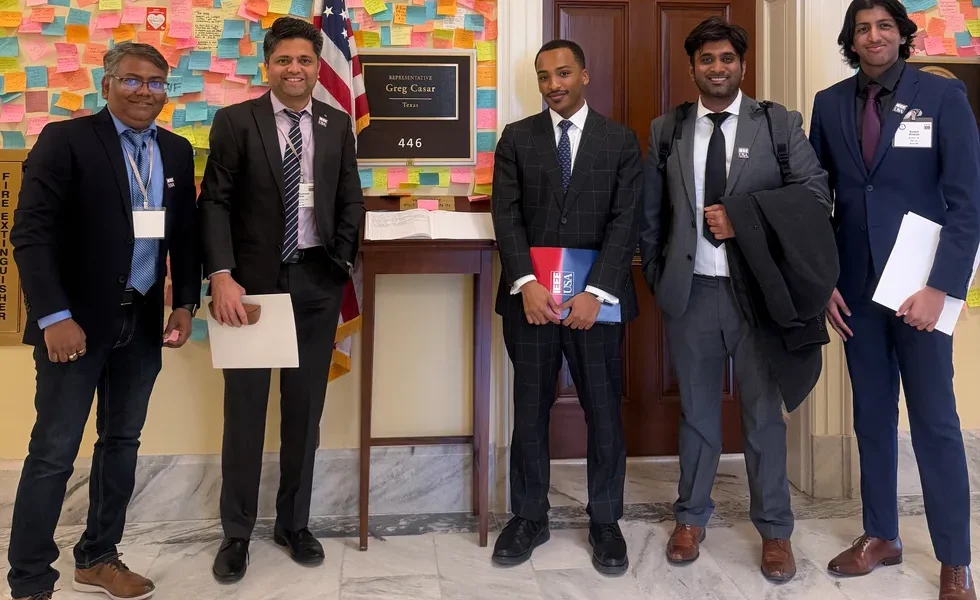 group of five men standing outside an office with a placard that reads representative greg casar tex
