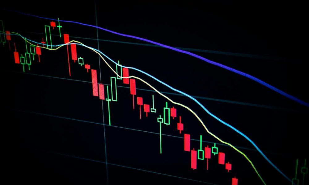 Stock market candlestick chart on dark screen showing decline
